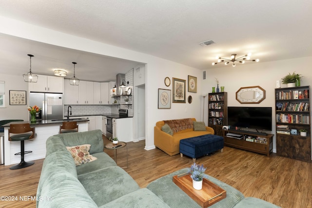 living room featuring a chandelier, sink, and light hardwood / wood-style flooring