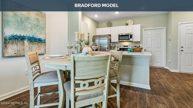 kitchen featuring appliances with stainless steel finishes, white cabinetry, dark wood-type flooring, and a breakfast bar area