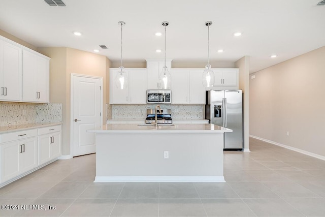 kitchen with a kitchen island with sink, white cabinets, hanging light fixtures, light tile patterned floors, and stainless steel appliances