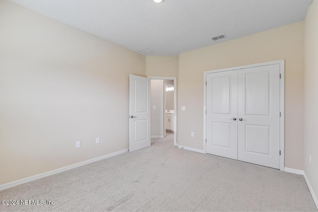 unfurnished bedroom featuring light carpet and a closet