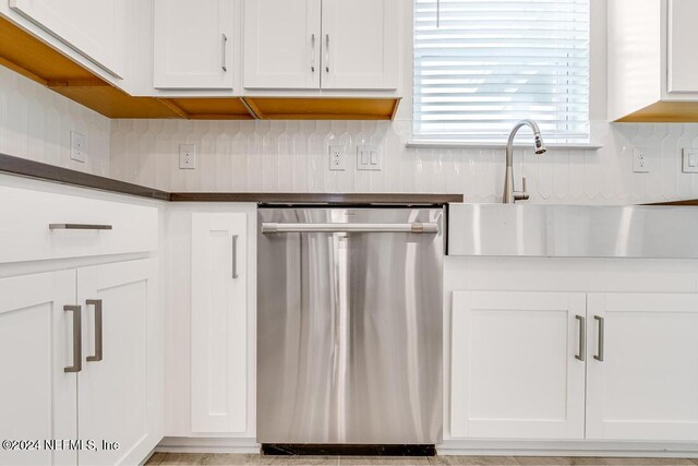 kitchen featuring white cabinets, backsplash, stainless steel dishwasher, and sink