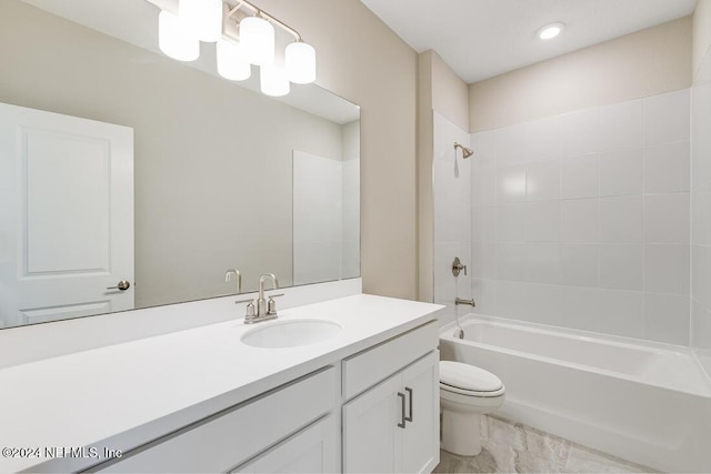 full bathroom featuring tiled shower / bath combo, toilet, and vanity