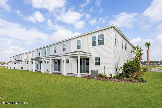 rear view of property featuring central air condition unit, a yard, and a patio