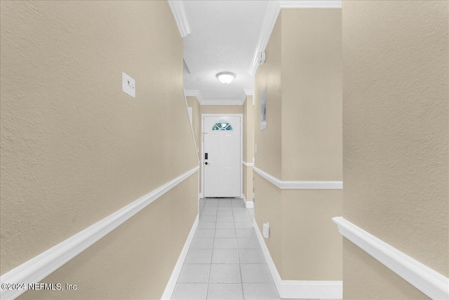 corridor featuring a textured ceiling, ornamental molding, and light tile patterned flooring