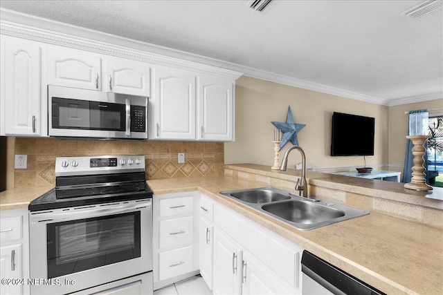 kitchen with crown molding, sink, decorative backsplash, appliances with stainless steel finishes, and white cabinetry