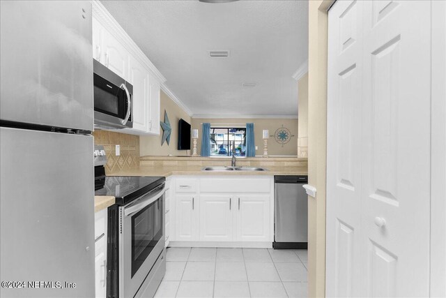 kitchen featuring crown molding, sink, tasteful backsplash, white cabinetry, and stainless steel appliances