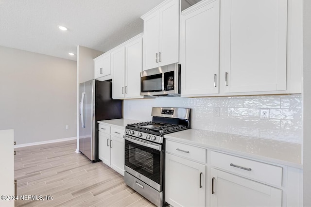 kitchen with white cabinets, light hardwood / wood-style floors, stainless steel appliances, and tasteful backsplash