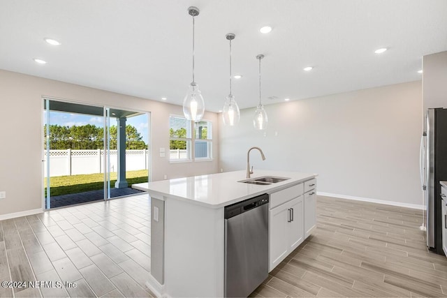 kitchen with stainless steel appliances, sink, pendant lighting, white cabinets, and an island with sink