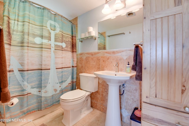 bathroom with tile patterned floors, toilet, walk in shower, and tile walls