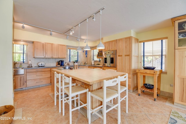 kitchen with backsplash, a kitchen bar, light brown cabinetry, and light tile patterned floors