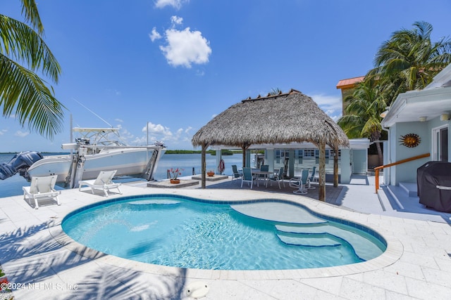 view of pool with grilling area, a gazebo, a water view, and a patio