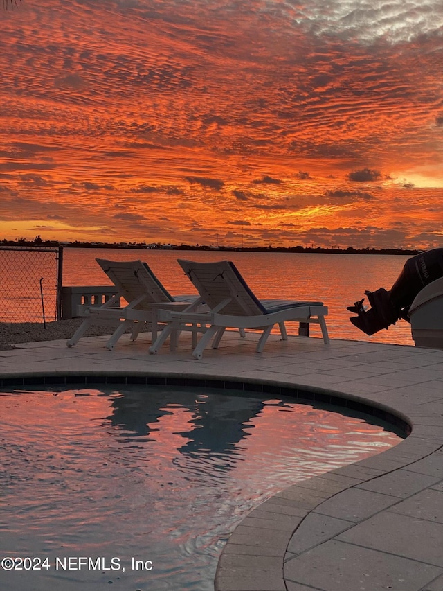 pool at dusk featuring a water view