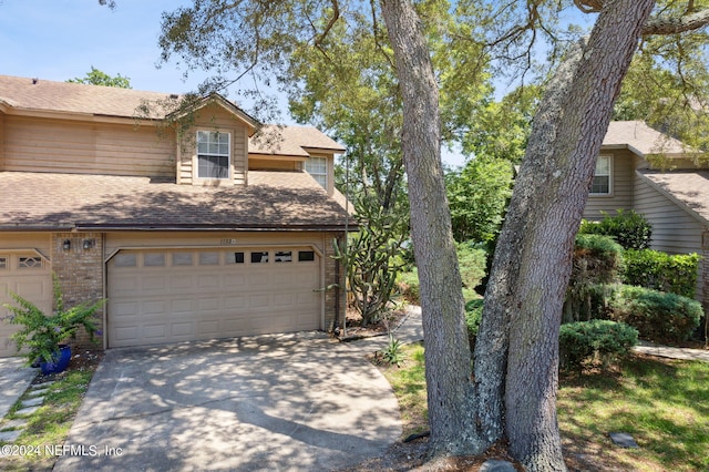 view of front of property featuring a garage, brick siding, roof with shingles, and concrete driveway