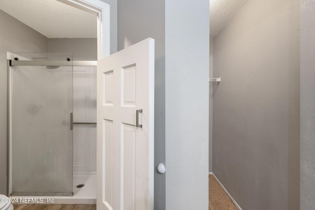 full bathroom with baseboards, a textured ceiling, and a shower stall