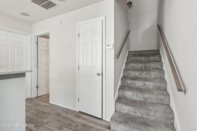 stairs with visible vents, baseboards, and wood finished floors