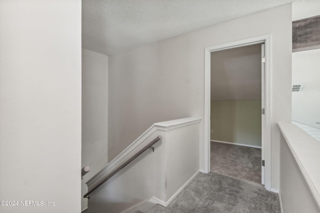 stairway with carpet flooring, a textured ceiling, and baseboards