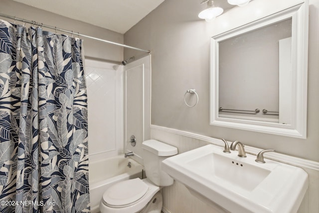 full bathroom with shower / tub combo, toilet, a wainscoted wall, and a sink