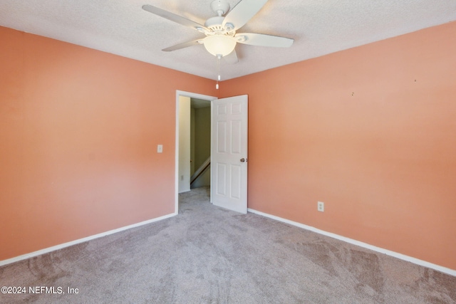 carpeted empty room with a ceiling fan, baseboards, and a textured ceiling