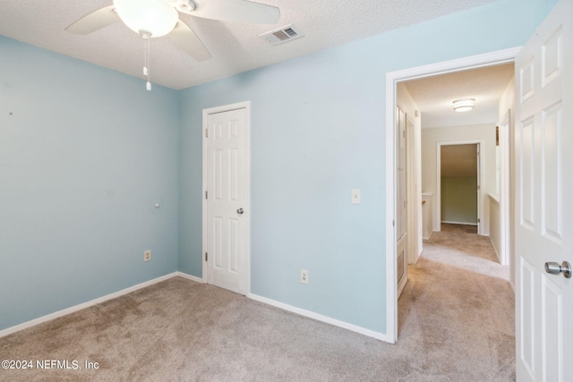 unfurnished bedroom with visible vents, a textured ceiling, a closet, carpet flooring, and baseboards