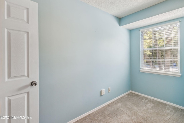 carpeted empty room featuring baseboards and a textured ceiling