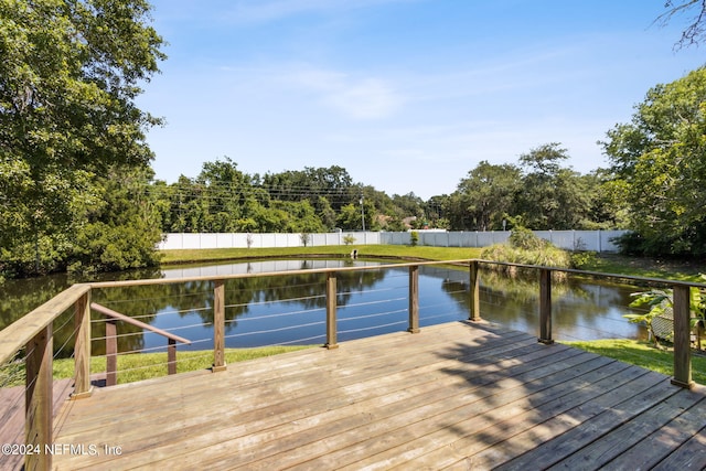 dock area with a deck with water view and a fenced backyard