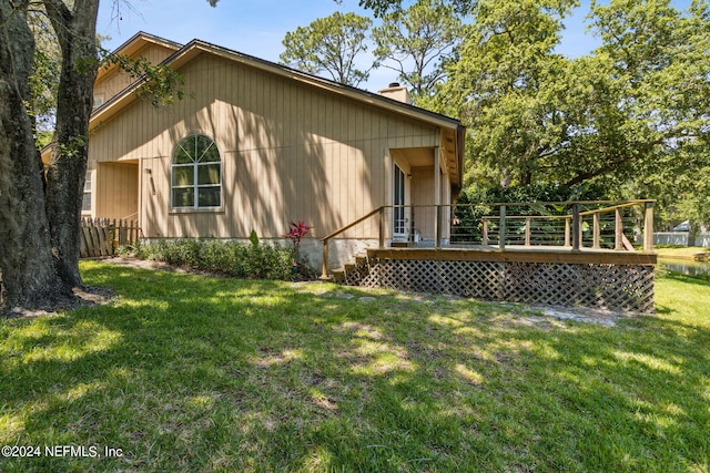 exterior space with a lawn, a chimney, and a wooden deck