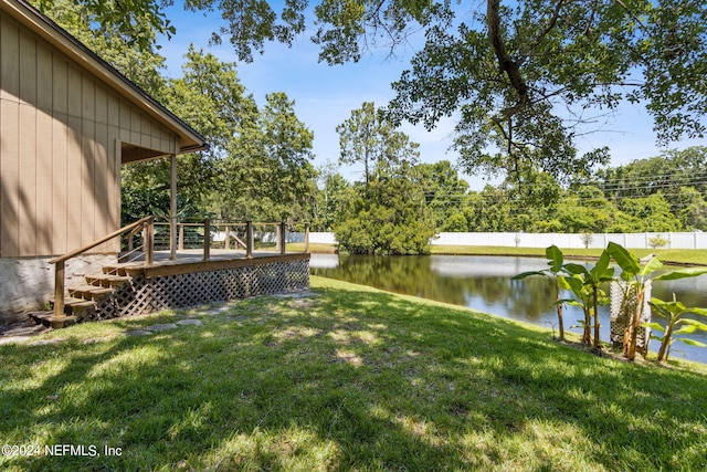 view of yard featuring fence and a deck with water view