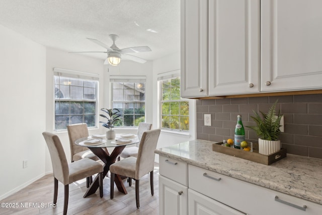 dining space with baseboards, a textured ceiling, a ceiling fan, and light wood finished floors