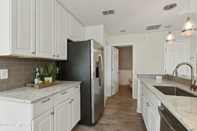 kitchen featuring visible vents, light wood-style flooring, stainless steel appliances, and a sink