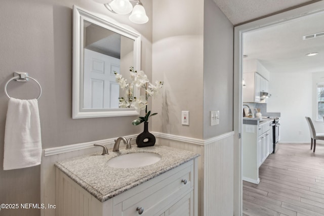 bathroom featuring visible vents, a wainscoted wall, wood finished floors, and vanity