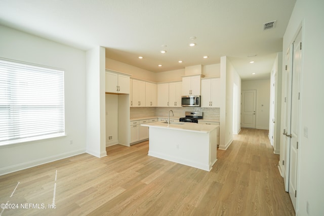 kitchen featuring sink, white cabinetry, stainless steel appliances, and a kitchen island with sink