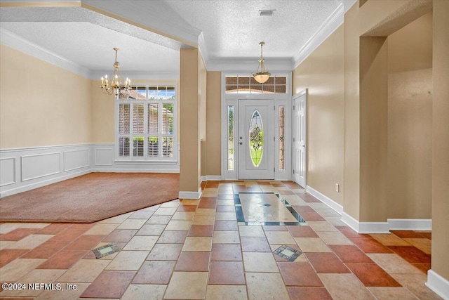 carpeted foyer entrance with ornamental molding, a textured ceiling, and a chandelier