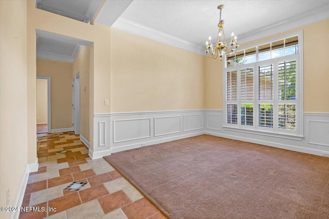 carpeted spare room featuring a textured ceiling, an inviting chandelier, and crown molding