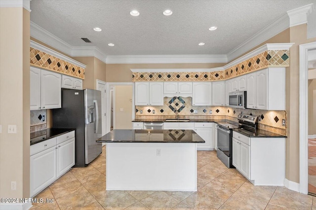 kitchen featuring white cabinetry, a center island, stainless steel appliances, a textured ceiling, and ornamental molding