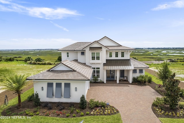 view of front of property with metal roof, a tiled roof, a rural view, decorative driveway, and stucco siding