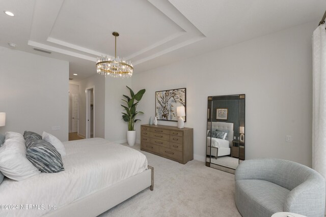 bedroom featuring a tray ceiling, a notable chandelier, and light colored carpet