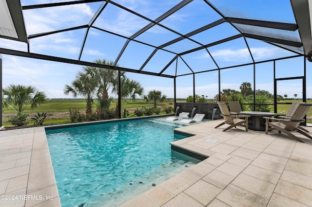 view of pool featuring glass enclosure, pool water feature, and a patio area