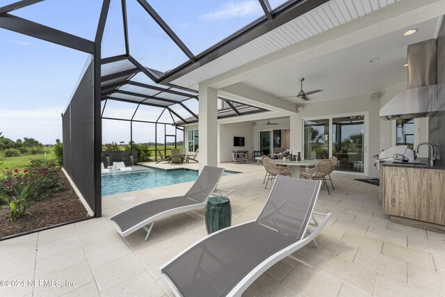 view of swimming pool featuring a patio area, sink, glass enclosure, and ceiling fan