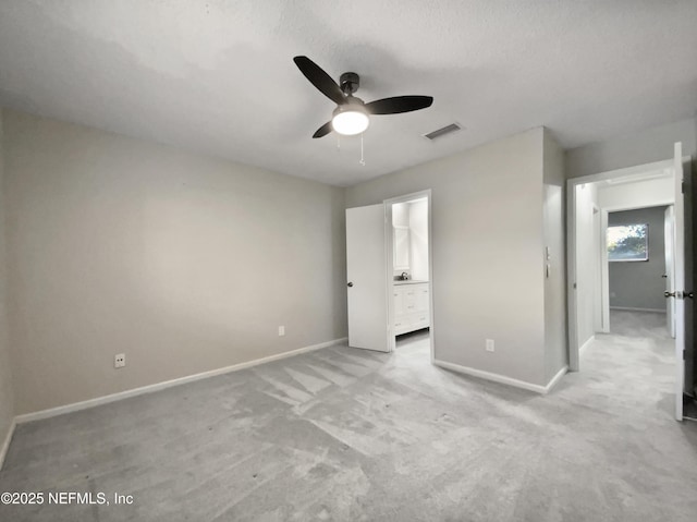 unfurnished bedroom with ceiling fan, ensuite bathroom, light carpet, and a textured ceiling