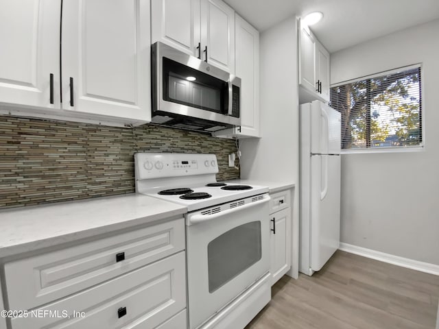 kitchen with tasteful backsplash, white cabinets, white appliances, and light wood-type flooring