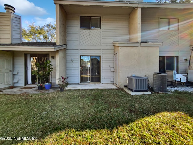 rear view of property with central air condition unit and a lawn