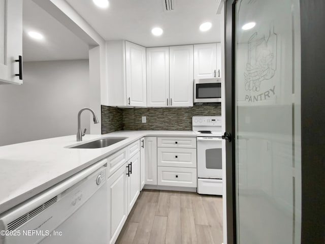 kitchen featuring white appliances, white cabinets, sink, light hardwood / wood-style flooring, and decorative backsplash