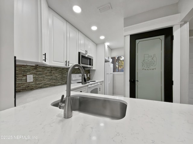 kitchen featuring white cabinets, sink, light stone countertops, tasteful backsplash, and white fridge