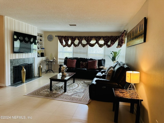 living room featuring a tile fireplace, built in features, and a textured ceiling