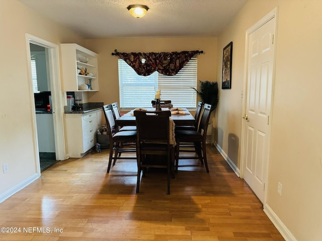 dining area with a textured ceiling and light hardwood / wood-style floors