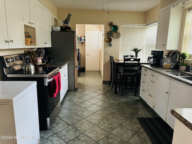 kitchen featuring stainless steel refrigerator, white cabinetry, sink, tile patterned flooring, and electric stove