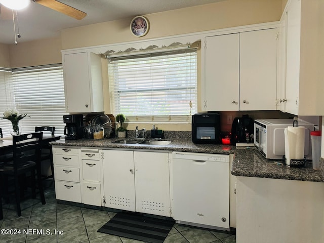 kitchen with dark tile patterned flooring, white cabinetry, white appliances, and sink