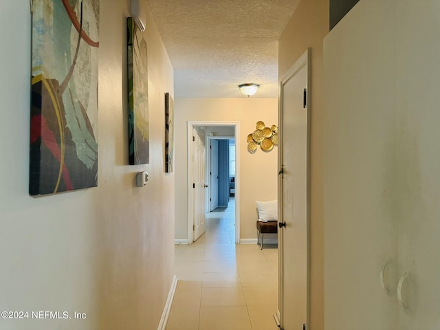 hall featuring light tile patterned floors and a textured ceiling