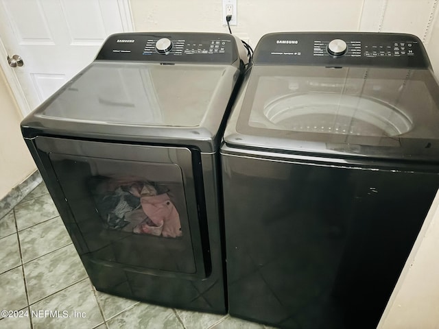 clothes washing area featuring washing machine and clothes dryer and tile patterned floors