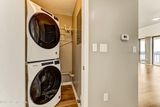 clothes washing area with wood-type flooring, a textured ceiling, and stacked washer and clothes dryer